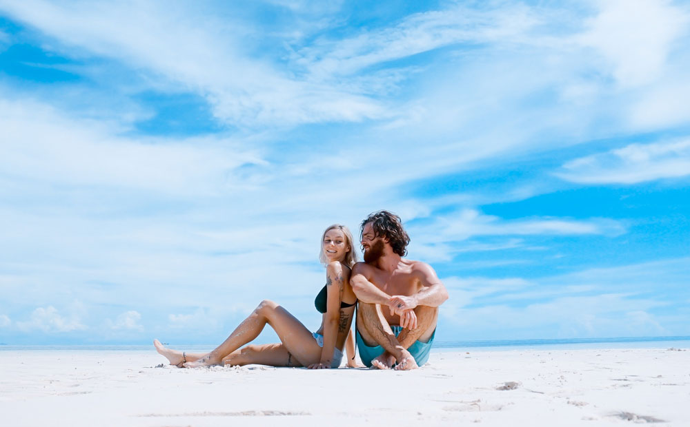 Male and female sitting on beach