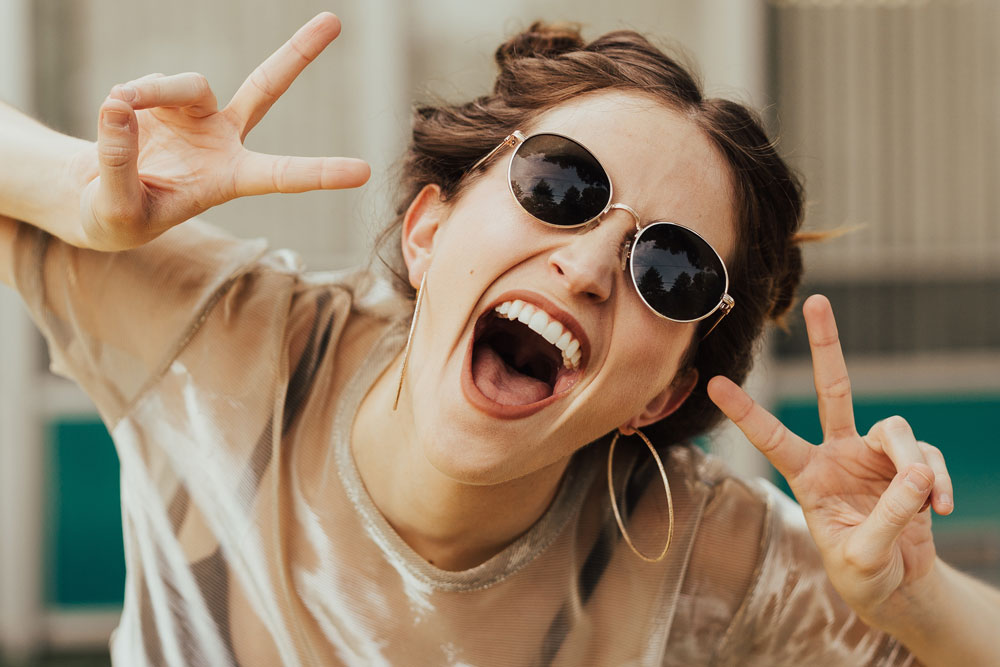 selective focus photography of jolly woman using peace hand gesture