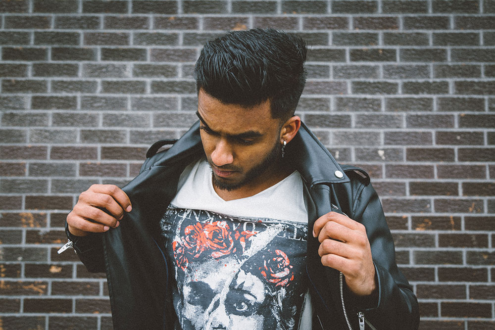 person wearing black jacket on whit white shirt in front of brick wall