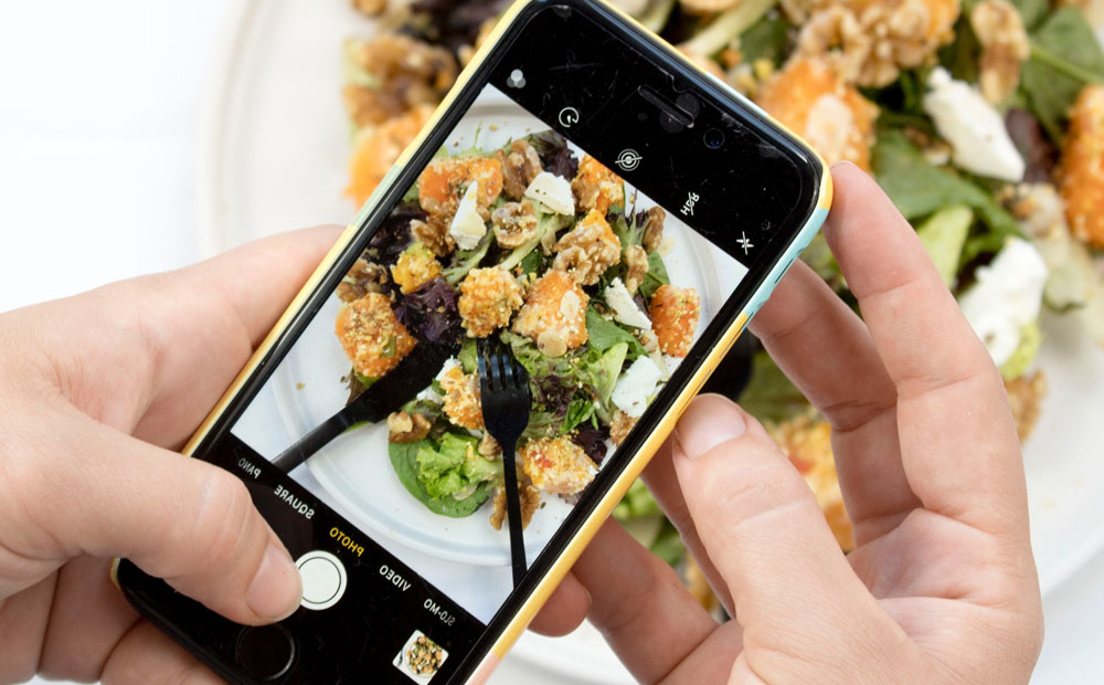 person using iPhone taking picture of food