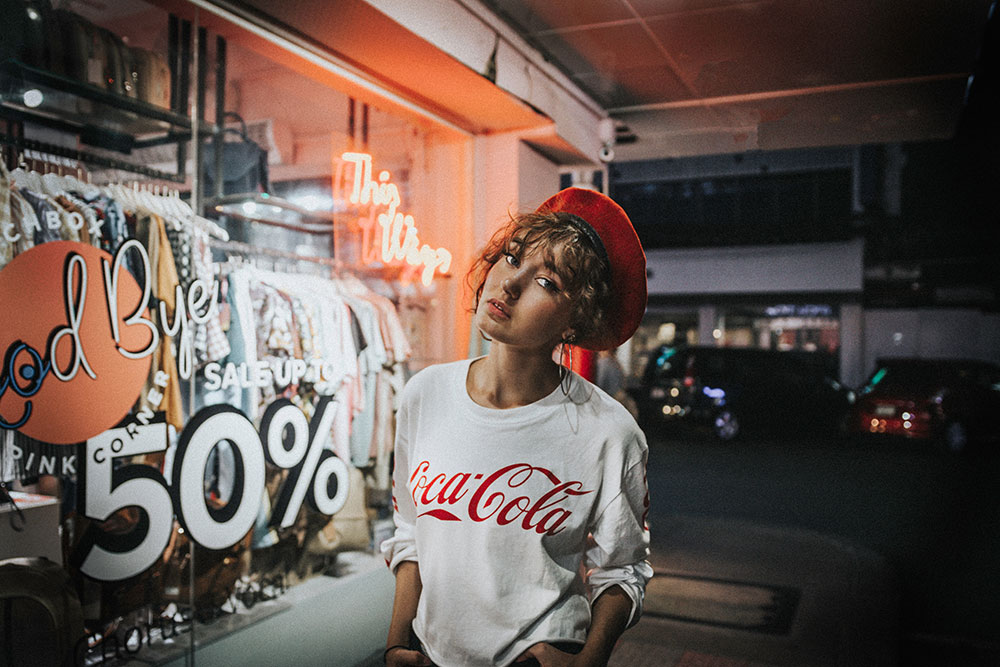 Woman in front of store wearing a red beret and a Coca-Cola sweater